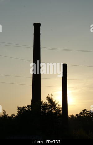 Alba con due vecchie abbandonato il fumo della fabbrica di pile in un piccolo industriale cittadina della Georgia. Foto Stock