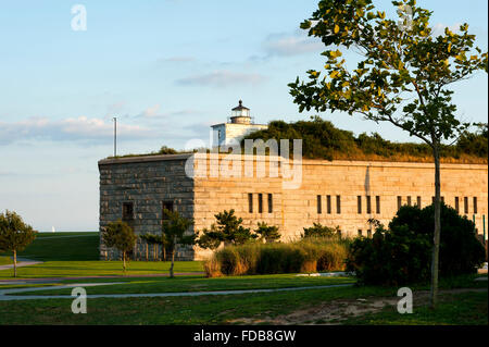 La vecchia torre del faro di Clark punto luce si siede sulla cima di pietra costruiti Fort Taber come il sole tramonta, illuminando il parco in un bagliore dorato. Foto Stock