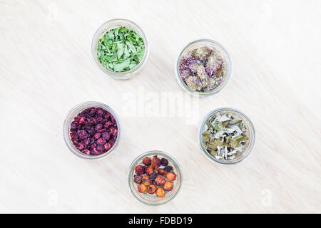 Appartamento Foto laici di wildcrafted essiccati ingredienti tè (menta, lampone foglie, trifoglio rosso, rosa canina, mirtilli) in vasi su un wo Foto Stock