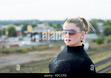 Il ritratto di donna sul ponte contro binari ferroviari Foto Stock