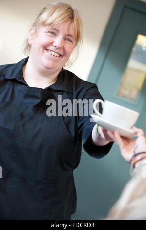 Cameriera in cafe consegnando il cliente una tazza di tè. Foto Stock