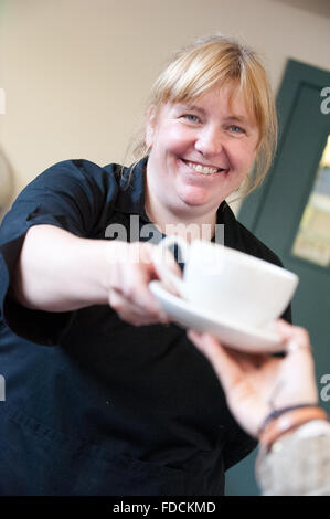 Cameriera in cafe consegnando il cliente una tazza di tè. Foto Stock