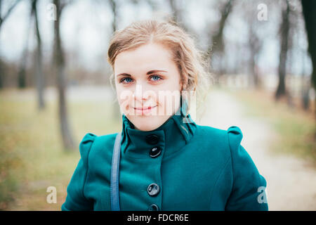 Ritratto di belle dimensioni più giovane donna in Blue Coat in posa di parco. Primavera, Autunno ritratto all'aperto Foto Stock