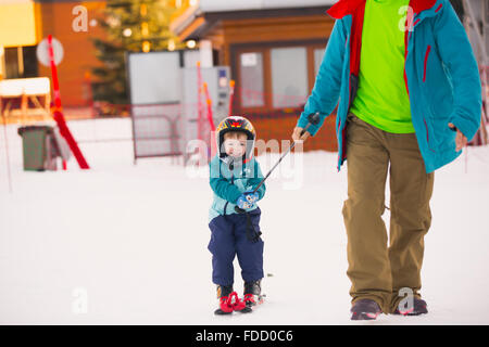 Bella giovane papà e il suo bambino boy, sci in montagna Foto Stock