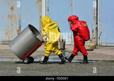 Lavoratori in uniforme di protezione,maschera,guanti e stivali barili di trasporto di sostanze chimiche Foto Stock