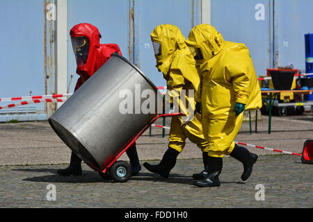 Lavoratori in uniforme di protezione,maschera,guanti e stivali barili di trasporto di sostanze chimiche Foto Stock