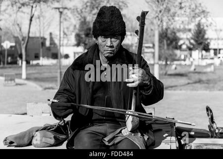 Zhongwei, Cina - Gennaio 2016. Musicista di strada la riproduzione del Erhu su un pomeriggio freddo. Foto Stock