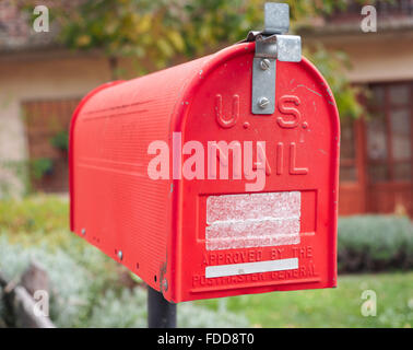 Una vecchia casa letter box dipinto di rosso, con lo sfondo della casa rurale Foto Stock