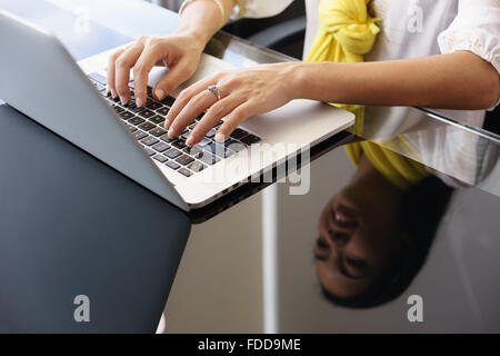 Primo piano delle mani del giovane donna adulta lavora come assistente in un ufficio moderno. L'imprenditrice scrive sul pc laptop e sorrisi. R Foto Stock