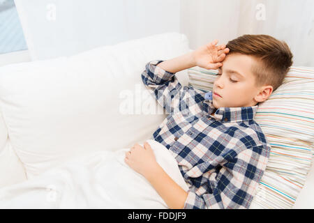 Ragazzo malato che giace nel letto e che soffrono di mal di testa Foto Stock