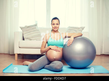 Felice donna incinta con fitball a casa Foto Stock