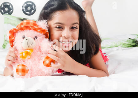 Un bambino ragazza camera da letto sdraiato relax azienda giocattolo Foto Stock