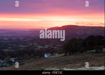 Distanza lunga vista sulla valle Wharfe, nello Yorkshire, Inghilterra, GB, UK, dall alto Burley Moor presso sunrise, con un drammatico rosa, rosso e arancione del cielo. Foto Stock