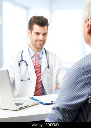 Medico maschio consultando il suo paziente anziano mentre sono seduti nella parte anteriore del computer. Foto Stock