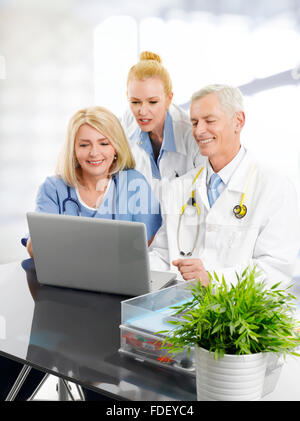 Gruppo del team medico seduto alla scrivania nella parte anteriore del computer portatile e consulting in ospedale. Foto Stock