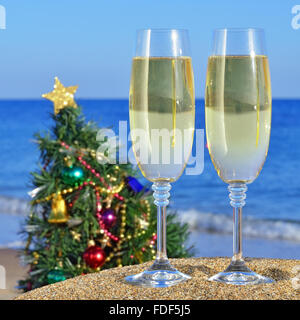 Seascape con bicchieri di champagne e un albero di Natale sulla spiaggia contro il blu del mare e del cielo Foto Stock