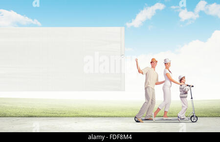 Immagine di felice famiglia giovane a cavallo su scooter tirando intestazione vuota Foto Stock