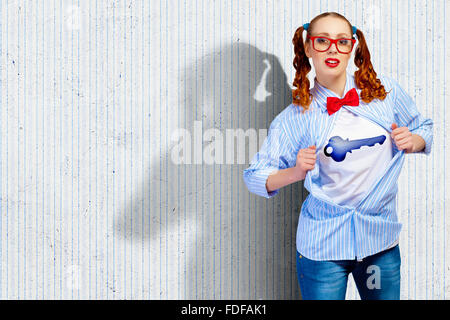 Giovane donna che agisce come super eroe con segno chiave sul petto Foto Stock