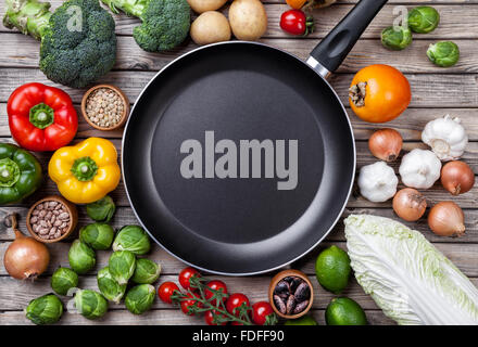 Vari ortaggi frutta ed erbe aromatiche con una padella su sfondo di legno Foto Stock