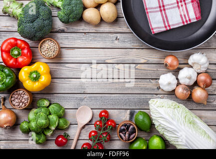 Vari ortaggi frutta ed erbe aromatiche con una padella su sfondo di legno Foto Stock