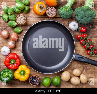 Vari ortaggi frutta ed erbe aromatiche con una padella su sfondo di legno Foto Stock