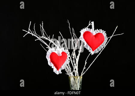 Due cuore rosso a forma di puntaspilli su un ramo di albero Foto Stock
