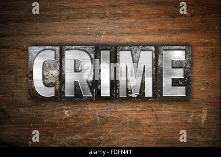 La parola "crimine" scritto in metallo vintage tipo di stampa in rilievo su un vecchio sfondo di legno. Foto Stock