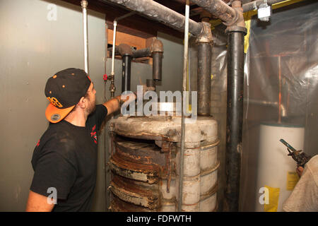 La rimozione di acqua di riscaldamento Tubazioni dal vecchio stile di gravità forno a gas durante il processo di sostituzione. St Paul Minnesota MN USA Foto Stock