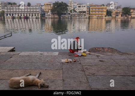 Una donna Indù facendo una puja una preghiera che offre sulle rive del Lago Pichola, Udaipur, India. Foto Stock