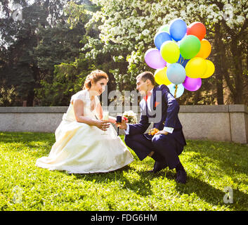 Felice sposa e lo sposo camminare insieme in un parco a molla con palloncini Foto Stock