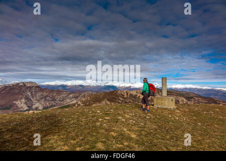 Femmina walker red zaino sulla cima delle colline sopra Tremp, Spagna con vista in lontananza snowy Pirenei Foto Stock