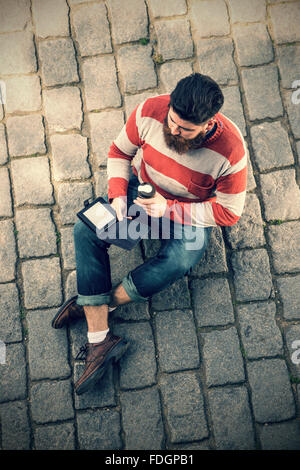 Giovane uomo parigamba utilizzando libro elettronico Foto Stock