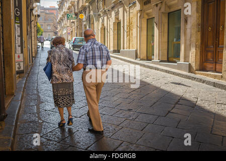 Coppia senior a piedi, vista posteriore di una coppia di anziani facendo la loro strada fino a Piazza Umberto I di Enna, Sicilia, per iniziare la passeggiata serale. Foto Stock