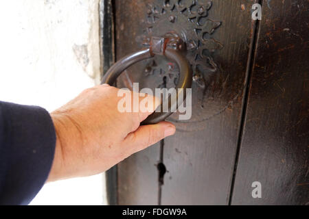 Tirando la porta, una mano d'uomo su un vecchio meccanismo di chiusura sportello. Foto Stock