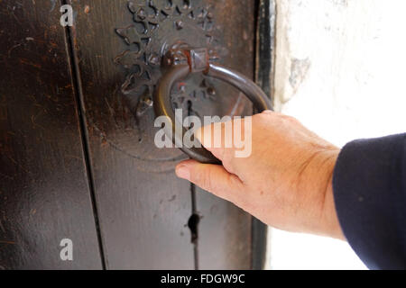 Tirando la porta, una mano d'uomo su un vecchio meccanismo di chiusura sportello. Foto Stock