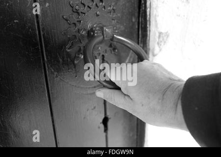 Tirando la porta, una mano d'uomo su un vecchio meccanismo di chiusura sportello. Foto Stock