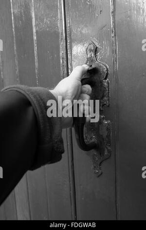 Tirando la porta, una mano d'uomo su un vecchio meccanismo di chiusura sportello. Foto Stock