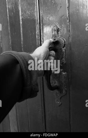 Tirando la porta, una mano d'uomo su un vecchio meccanismo di chiusura sportello. Foto Stock