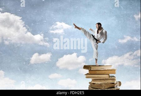 Giovani determinato karate uomo sulla pila di libri Foto Stock