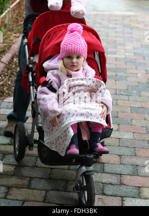 Bambina kid, bambino indossando un inverno bobble hat in seduta il buggy con la sua blankie di andare a fare una camminata su una inverni freddi giorno Foto Stock