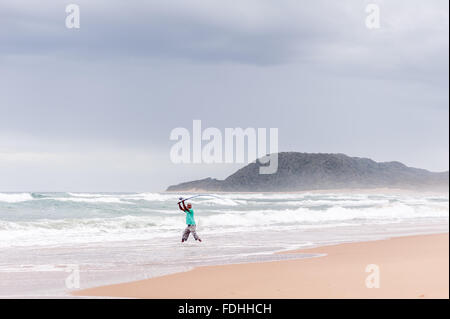 Un uomo con attività di pesca nell'oceano in Saint Lucia, Kwazulu-Natal, Sud Africa - iSimangaliso Wetland Park Foto Stock