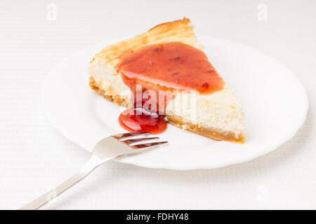 Pezzo di cheesecake su bianco piattino sul tavolo Foto Stock