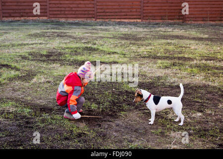 Bambina con un cane a giocare con bastoni di legno Foto Stock