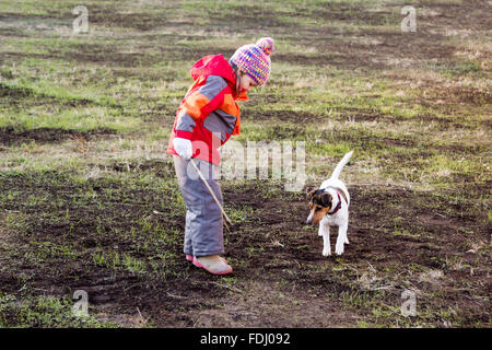 Bambina con un cane a giocare con bastoni di legno Foto Stock