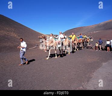 I turisti facendo un giro in cammello attraverso il Parco Nazionale di Timanfaya, Lanzarote, Isole Canarie, Spagna. Foto Stock