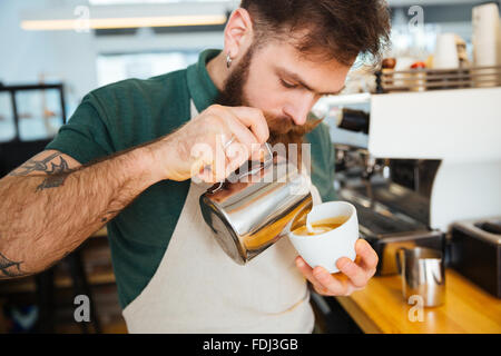 Barista rendendo cappuccino in coffee shop Foto Stock