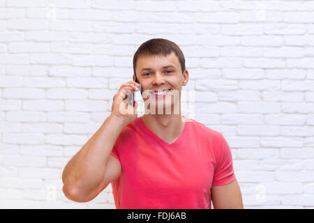 Uomo informale chiamata con il Cellulare Smartphone parlare stando in piedi sopra la parete Foto Stock