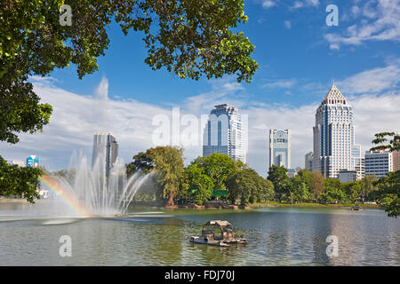 Fontana nel mezzo del lago nel Parco Lumphinee con alti edifici moderni in background. Bangkok, Tailandia. Foto Stock