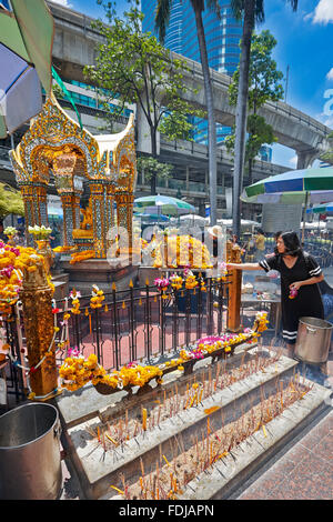 Una donna fa offerte al Santuario Erawan, un santuario dedicato a Brahma a Bangkok, Thailandia. Foto Stock