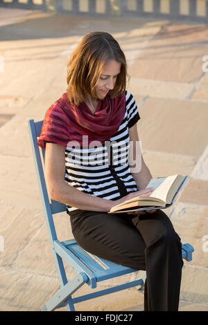 Giovane donna leggendo un libro all'esterno. Foto Stock